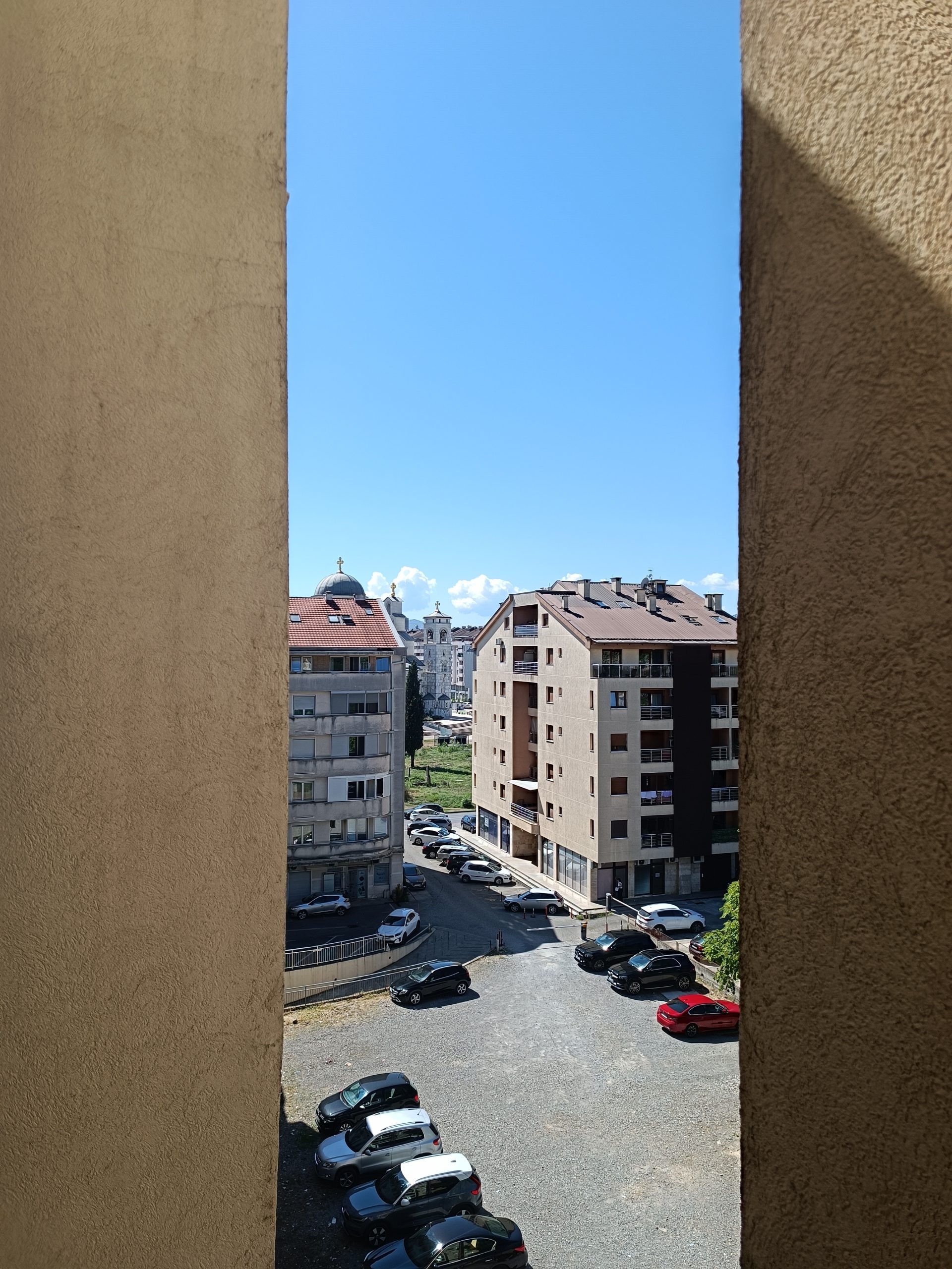 Najbolje nekretnine u Crnoj Gori - Pogled sa terase na okolne zgrade, parking i crkvu u pozadini